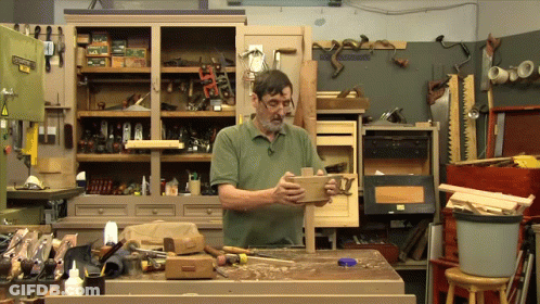 Man In Green Shirt Holding Piece Of Wood GIF