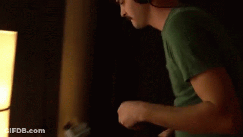 Man In Green Shirt Playing Guitar With Headphones GIF