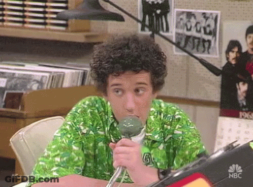 Man In Green Shirt Sitting At Table Holding Microphone GIF