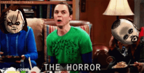 Man In Green Shirt Sitting On Couch With Two Dolls Saying The Horror GIF