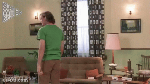 Man In Green Shirt Standing Next To Couch GIF