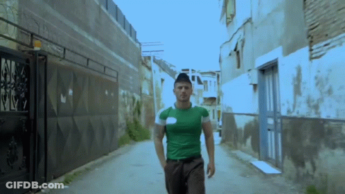 Man In Green Shirt Walking Alleyway GIF