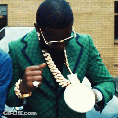 Man In Green Suit And Gold Chains Holding White Object GIF