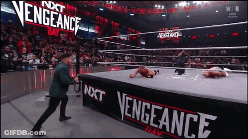 Man In Green Suit Standing Before Vengeance Sign GIF