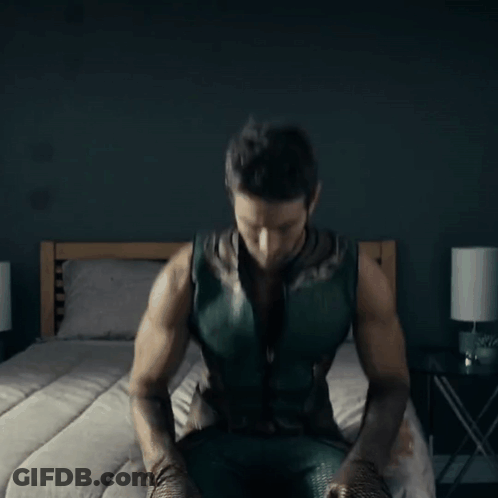 Man In Green Superhero Costume Sitting GIF