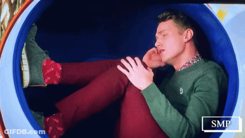 Man In Green Sweater And Red Pants Lying In Blue Circle GIF