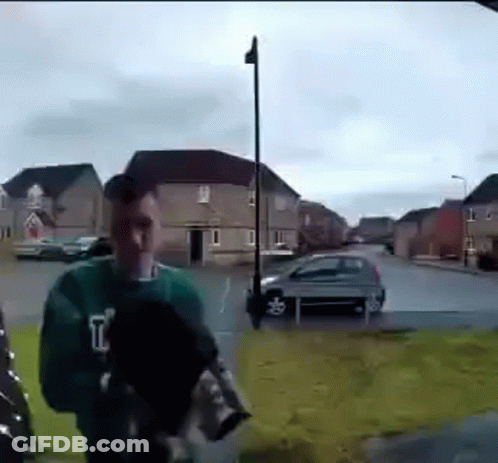 Man In Green Sweater On Sidewalk GIF