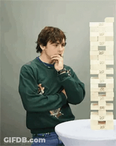 Man In Green Sweater Standing Next To Stack Of Blocks GIF