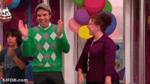 Man In Green Sweater Standing Next To Woman In Purple Dress GIF