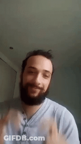 Man In Green Sweater With Sun Sits In Crowd GIF