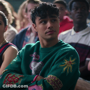 Man In Green Sweater With Sun Sits In Crowd GIF