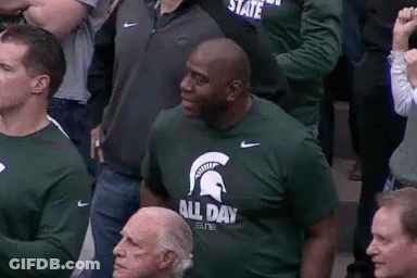 Man In Green T-Shirt With Spartan Helmet Sitting In Crowd GIF