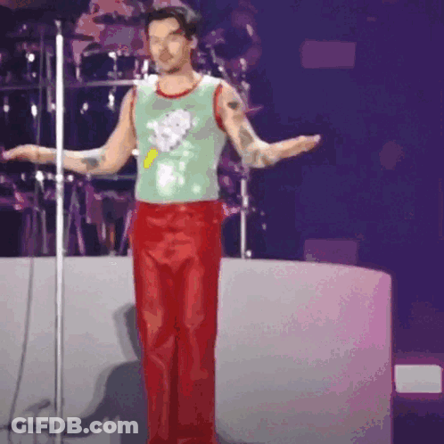 Man In Green Tank Top And Red Pants At Microphone GIF