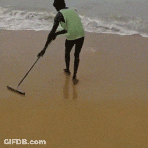 Man In Green Tank Top Standing On Beach GIF