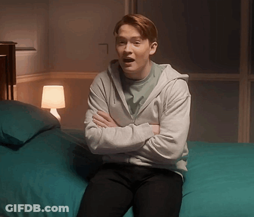 Man In Grey Hoodie Arms Crossed On Bed GIF