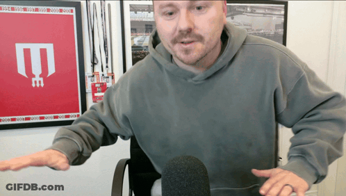Man In Grey Hoodie At Microphone GIF