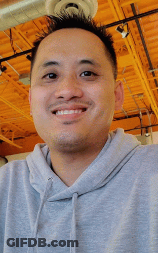 Man In Grey Hoodie Smiling Under Orange Ceiling GIF