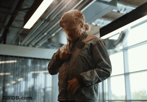 Man In Grey Jacket Standing In Front Of Glass Wall GIF