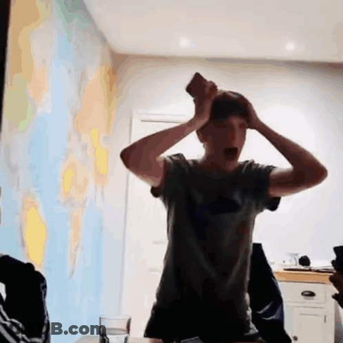 Man In Grey Shirt Holding Head In Front Of World Map GIF