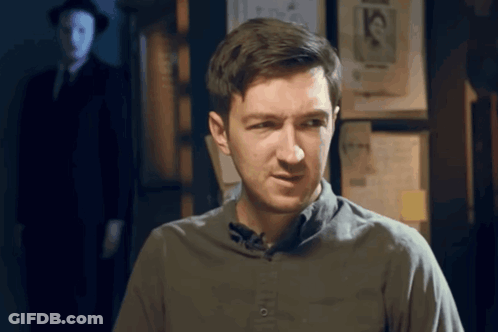 Man In Grey Shirt In Front Of Wall With Mask Picture GIF