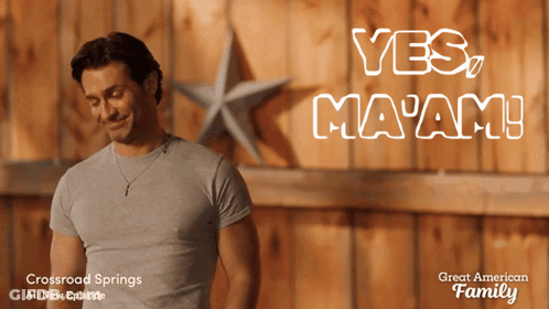Man In Grey Shirt In Front Of Yes Ma'am Wall GIF