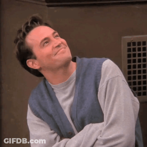Man In Grey Sweater And Blue Vest Smiling GIF