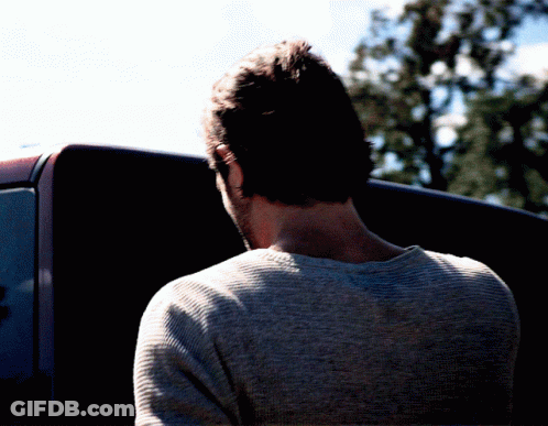 Man In Grey Sweater In Front Of Black Vehicle GIF