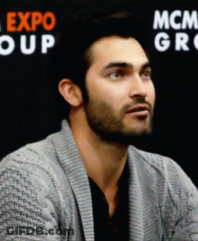 Man In Grey Sweater In Front Of Expo Group Sign GIF