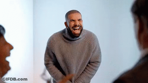 Man In Grey Sweater Laughing In Front Of Crowd GIF