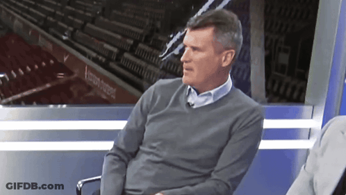 Man In Grey Sweater Sitting In Front Of Stadium Sign GIF