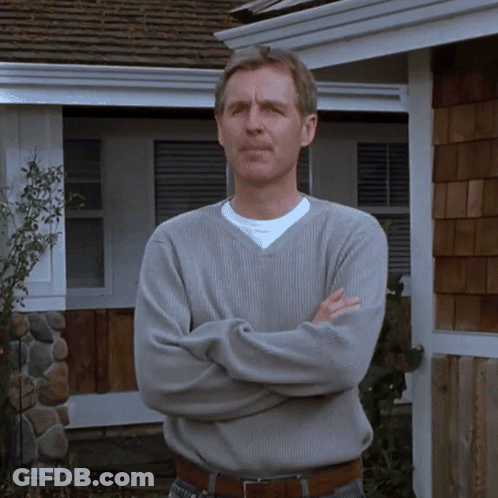 Man In Grey Sweater With Arms Crossed In Front Of House GIF