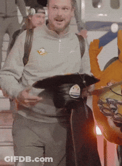 Man In Grey Sweatshirt With Bird Holding Black Hat GIF