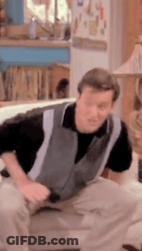 Man In Grey Vest Sitting On Couch GIF