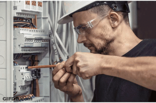 Man In Hard Hat And Safety Glasses Working On Circuit Board GIF