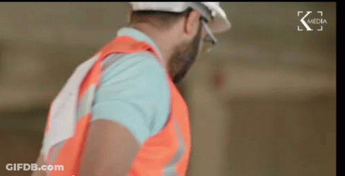 Man In Hard Hat And Safety Vest In Front Of K Media Screen GIF
