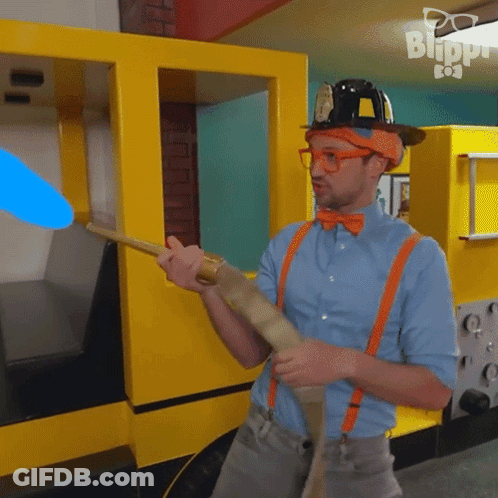 Man In Hard Hat And Suspenders Holding Stick In Front Of Blippi Building GIF