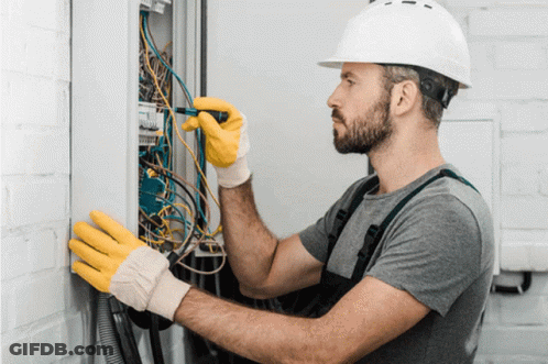 Man In Hard Hat And Yellow Gloves Working On Electrical Box GIF