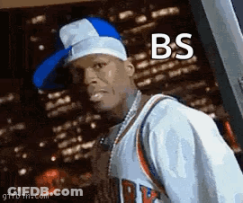 Man In Hat And Basketball Jersey Standing In Front Of Building GIF