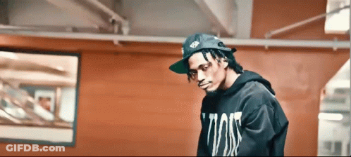 Man In Hat And Black Hoodie In Front Of Red Wall GIF