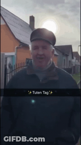 Man In Hat And Black Jacket In Front Of House Saying Tuten Tag GIF