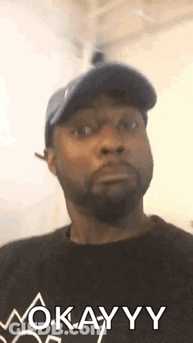 Man In Hat And Black Shirt Saying Okay GIF