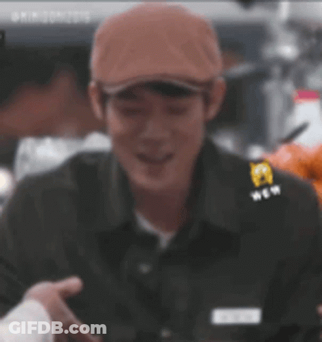 Man In Hat And Black Shirt Smiling Holding Hand GIF