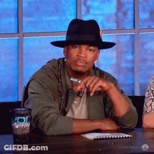 Man In Hat And Green Jacket Sitting With Hands Folded GIF