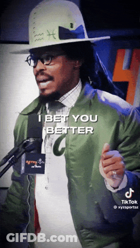 Man In Hat And Green Jacket Talking Into Microphone GIF