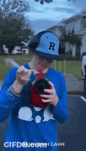 Man In Hat And Headphones Drinking With Spoon In Mouth GIF