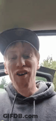 Man In Hat And Hoodie Making Funny Face In Car GIF