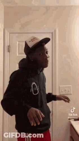 Man In Hat And Hoodie Standing In Bathroom GIF