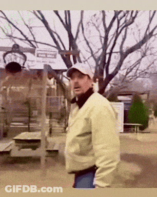 Man In Hat And Jacket Standing In Park GIF