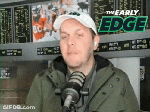 Man In Hat And Jacket Talking Into Mic GIF
