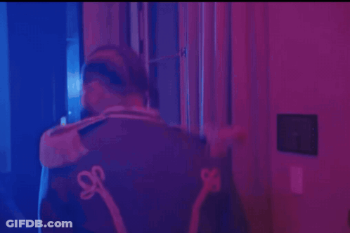 Man In Hat And Jacket With S On Back In Purple Room GIF